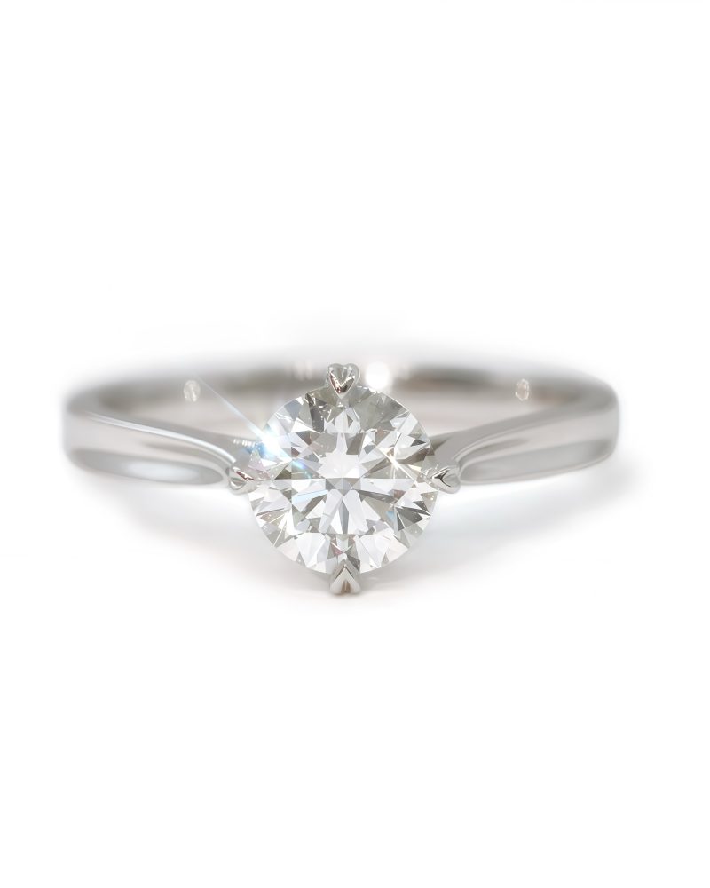 A solitaire diamond engagement ring in white gold, featuring a round brilliant-cut diamond in a prong setting against a solid white background. 白金單鑽求婚戒指，爪鑲單顆圓形明亮式切割鑽石，背景為純白色。