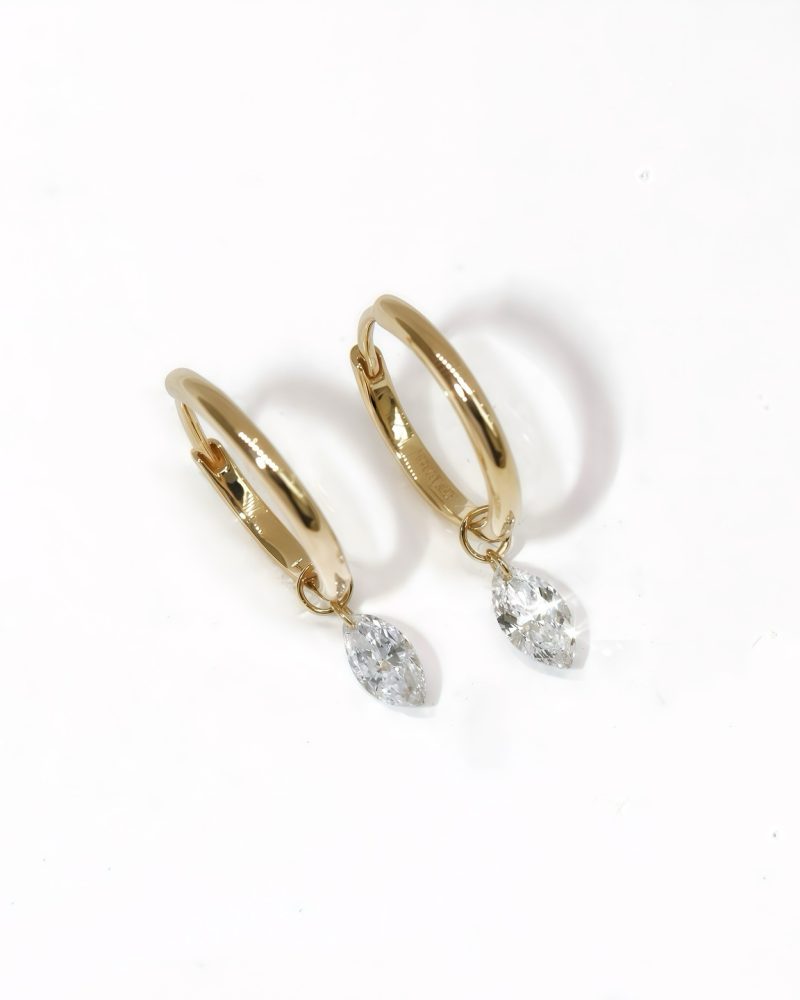 Pair of polished k yellow gold hoop earrings, each featuring a small dangling marquise-cut solitaire diamond charm, displayed on a plain white background. K黃金圈耳環商品圖，展示亮面黃金圈身搭配懸掛式馬眼形切工（Marquise-cut）單鑽吊飾，背景為純白色。
