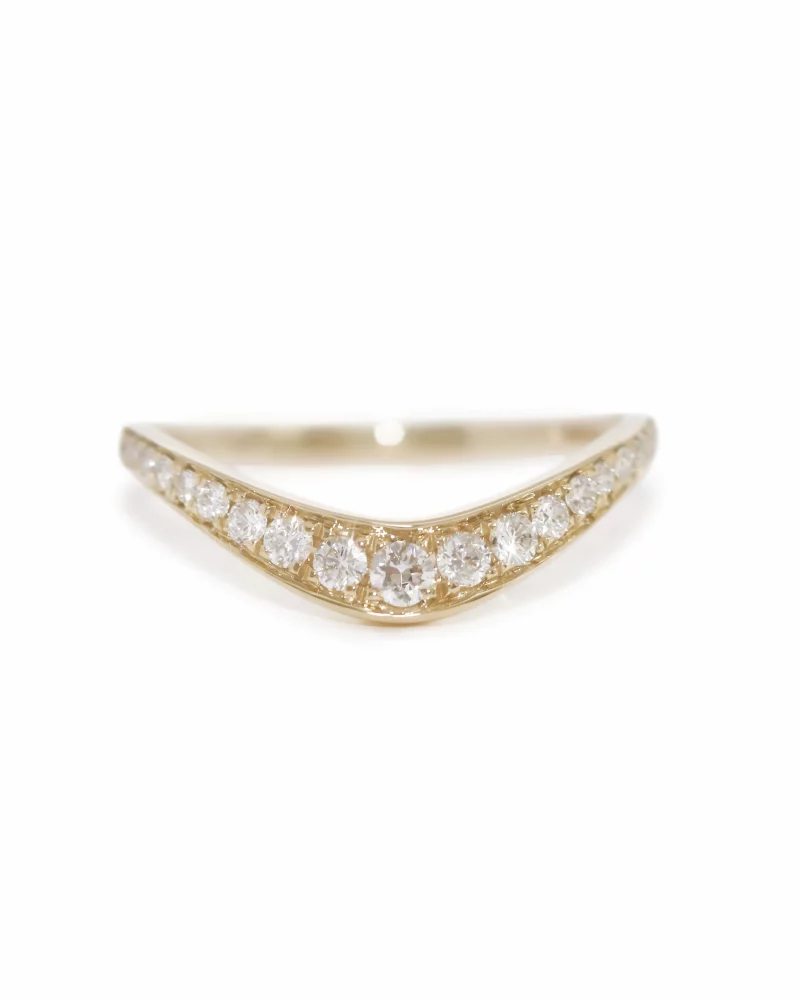 A delicate 18K/ 14k/ 9K yellow gold chevron diamond contour band featuring a row of pave-set round brilliant diamonds, isolated on a clean white background. 白底上一枚精緻的 18K/ 14K/ 9K 黃金 V 型弧形排戒，流線戒指正面並排鑲嵌著多顆圓形明亮式切割鑽石，展現優雅璀璨的貼合設計。